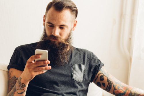 Mann med tatoveringer og mobiltelefon